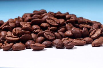 beautiful coffee beans are sprinkled on a white table with a blue background