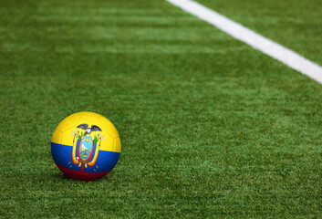 Ecuador flag on ball at soccer field background. National football theme on green grass. Sports competition concept.