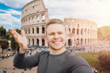 Happy young man making selfie and smile Colosseum in Rome, Italy. Concept travel