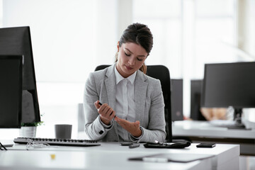 Beautiful businesswoman using lancet pen in office. Young woman checking blood sugar level	