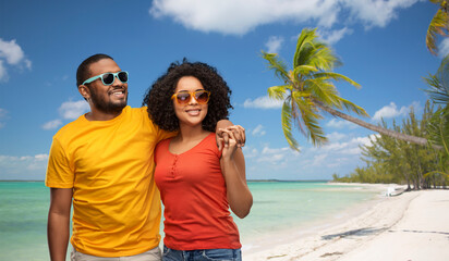 summer, relationships and people concept - happy african american couple in sunglasses over tropical beach background in french polynesia