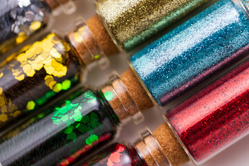 party, decoration and holidays concept - close up of different color glitters in small glass bottles with cork stoppers