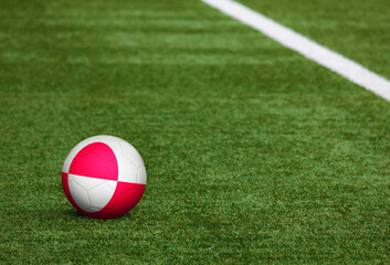 Greenland flag on ball at soccer field background. National football theme on green grass. Sports competition concept.