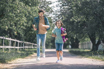 Dark-haired boy and his father running in the park