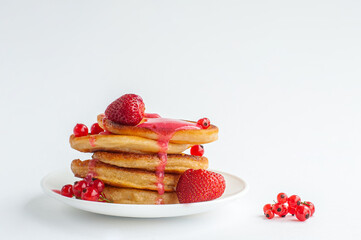 The pancakes are poured with red strawberry jam on a white background.
