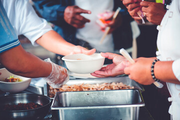 Hands of volunteers serves free food to the poor