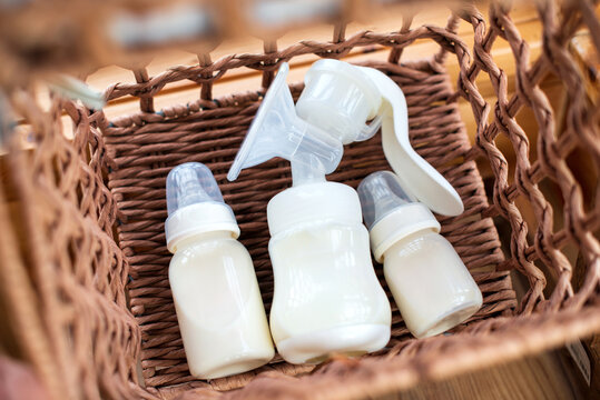 Breast pump and bottle with breast milk for baby in straw basket. Maternity and baby care concept. Top view.
