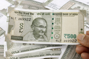 Indian currency notes of various denominations. Indian five hundred rupees note in hand with other denominations in background. 