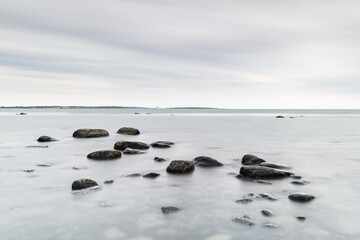 Stones lying in ocean with grey sky, Sweden.