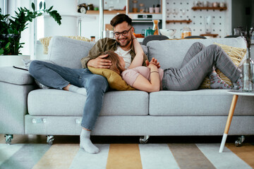 Husband and wife enjoying on sofa. Happy couple relaxing in living room.	