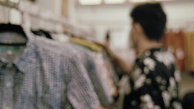 Hombre caucásico con camisa vintage comprando ropa en una tienda de ropa vintage con mascarilla covid coronavirus