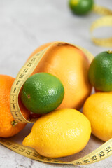 Lemons, oranges, grapefruits, limes and measuring tape on a concrete background.