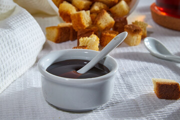 Liquid honey in a white plate and Square toasted pieces of homemade delicious rusk, hardtack, Dryasdust, zwieback on a white tablecloth.