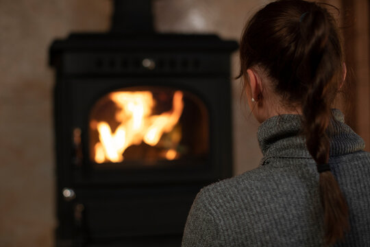 Portrait of pretty caucasian girl spending time in the evening at home by the fireplace. Relaxing by the fireplace and reading books in the evenings. Home rest in the winter.