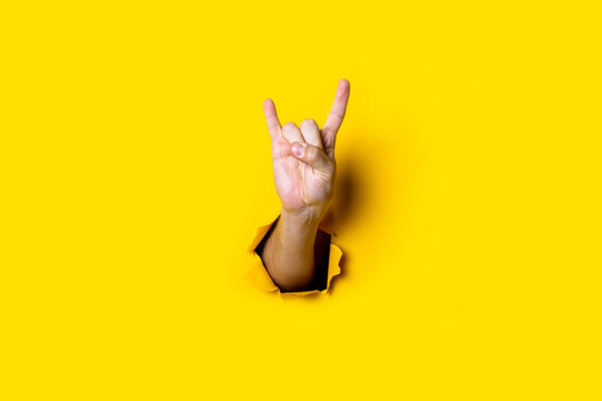 Male Hand Shows The Gesture Of Goat, Rocker Goat, Horns On A Yellow Background. Hand Gestures