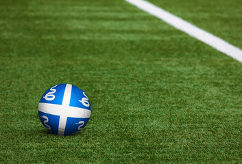 Martinique flag on ball at soccer field background. National football theme on green grass. Sports competition concept.