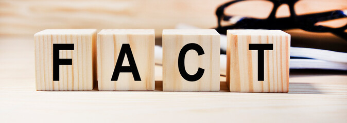 On the dice the word FACT, on the background of the notebook and glasses.