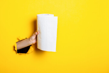 Woman's hand holds white paper towels on a torn yellow background