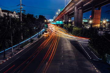 Fototapeta na wymiar Car lights at night on the road going to the city. Aerial view of the speed traffic trails on motorway highway in Bang Kho Laem, Rama 3, Bangkok, Thailand. Long exposure abstract urban background.