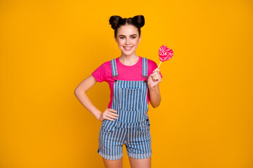 Portrait of her she nice attractive pretty charming cute lovely cheerful cheery girl eating tasty heart candy isolated on bright vivid shine vibrant yellow color background