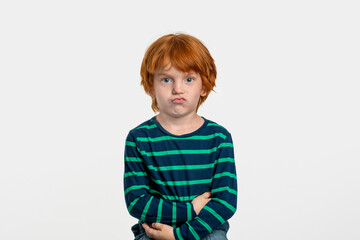  Redhead boy  stands arms crossed and looks offended at the camera
