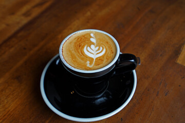 Close up ceramic cup of hot Latte coffee art on wooden table