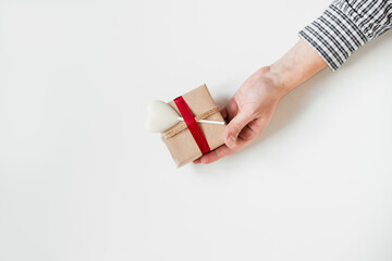 Gift box with heart,wrapped in craft paper with red ribbon and twin. Present box white background. Holiday present in hand. Valentines. Copy space