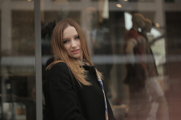 Fototapeta premium The girl in black coat. Beautiful emotional young girl in the city. Shawl or handkerchief on a person. 