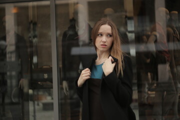 The girl in black coat. Beautiful emotional young girl in the city. Shawl or handkerchief on a person. 