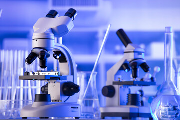 Coronavirus pandemic theme. Science research concerning fast covid tests and anti-covid vaccine. Beakers, microscope and test tubes on blue background.