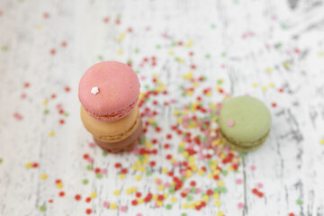 overhead view of three macaroons on a rustic white wooden table with many decorative colored stars