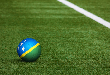 Fototapeta na wymiar Solomon Islands flag on ball at soccer field background. National football theme on green grass. Sports competition concept.