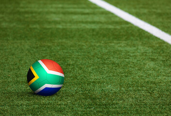Fototapeta na wymiar South Africa flag on ball at soccer field background. National football theme on green grass. Sports competition concept.