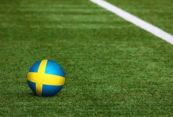 Fototapeta na wymiar Sweden flag on ball at soccer field background. National football theme on green grass. Sports competition concept.