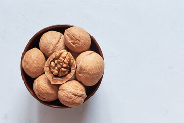 Walnuts in a brown wooden bowl on a gray background. Top view