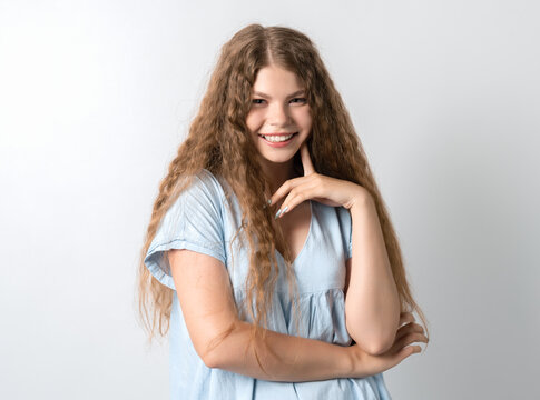 Photo of thoughtful European young woman with curly long hair looks with dreamy expression aside. Isolated over white background.