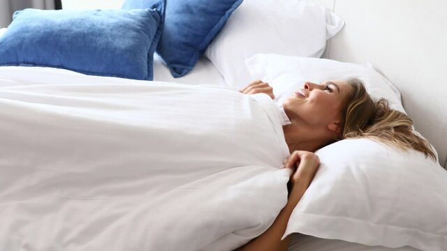 Beautiful sexy female slowly enjoy bedtime, show sexy body in white lingerie then cover it with blanket and stretching with smile