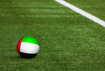 Fototapeta na wymiar United Arab Emirates flag on ball at soccer field background. National football theme on green grass. Sports competition concept.