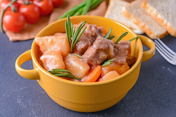 Pot with tasty beef stew on dark background