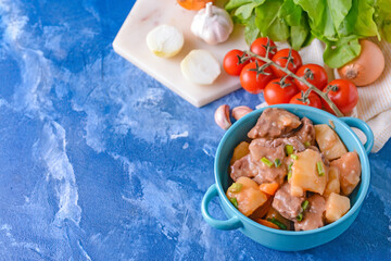 Pot with tasty beef stew on color background