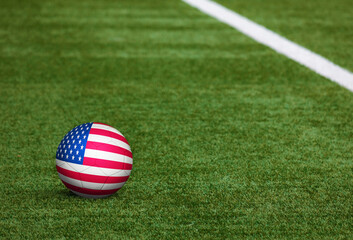 United States flag on ball at soccer field background. National football theme on green grass. Sports competition concept.