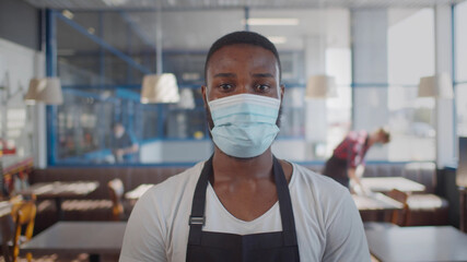 Portrait of afro-american waiter wearing protective mask looking at camera