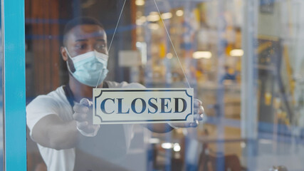 African waiter in mask and gloves putting open sign on cafe door