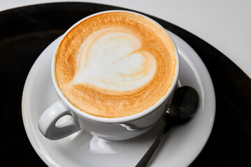 A cup of coffee. Latte with heart pattern in a white cup on black-white background