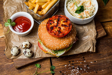 Hamburger with tomato sauce and fries, on a wooden table