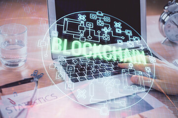 Blockchain theme hologram with man working on computer on background. Concept of crypto chain. Double exposure.