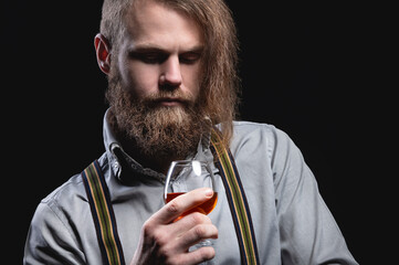 An attractive man with a long bang beard and a mustache sitting against the wall sniffs the scent...
