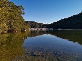 Early morning view of a creek with beautiful reflections of blue sky, boats, mountains and trees on water, Cowan Creek, Bobbin Head, Ku-ring-gai Chase National Park, New South Wales Australia