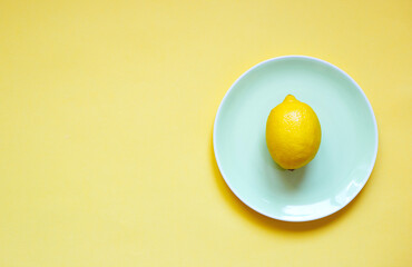 ripe lemon on a green plate on a yellow background