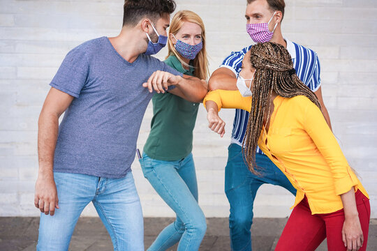 Young people friends bump their elbows instead of greeting with a hug wearing face mask - Avoid the spread of coronavirus, social distance and friendship concept - Main focus on left man hand